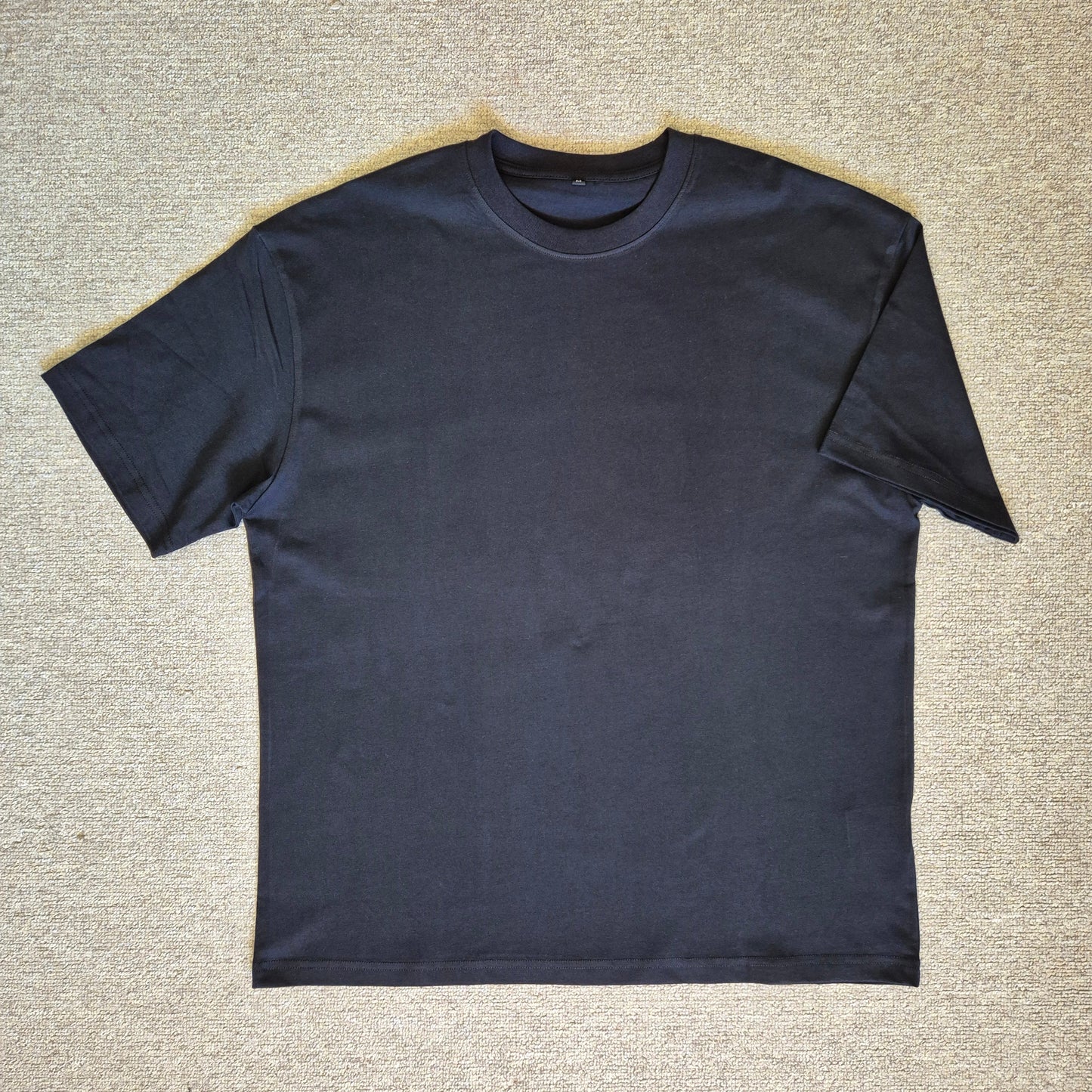 Black t-shirt on a textured beige surface